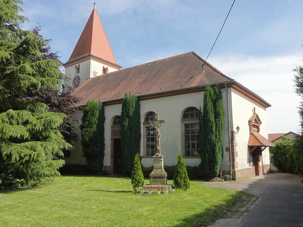 Photographie professionnelle d'une fresque murale de Jako Custom réalisée à Geudertheim ou dans une commune alsacienne proche, montrant un travail de graffiti/art urbain de qualité professionnelle sur la façade d'un bâtiment local. L'image doit capturer la fresque dans son intégralité, bien éclairée, avec en arrière-plan l'architecture alsacienne caractéristique du village (bâtiments typiques, architecture régionale). La scène doit clairement illustrer l'intervention locale de l'artiste sur le territoire alsacien.